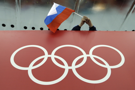 This Feb. 18, 2014 photo a Russian skating fan holds the country's national flag over the Olympic rings before the start of the men's 10,000-meter speedskating race at the 2014 Winter Olympics in Sochi, Russia. | AP