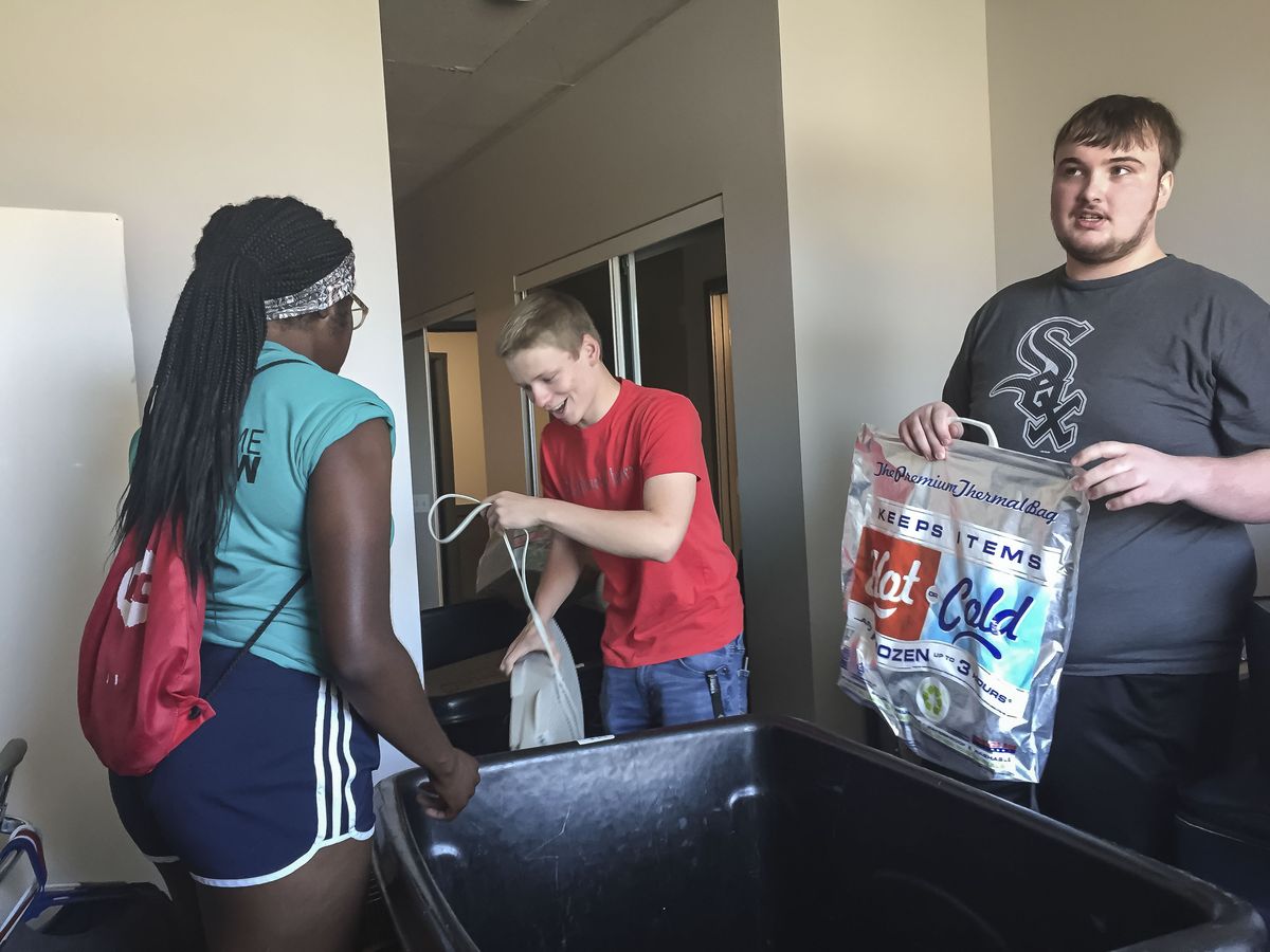 UIC students Anthony Abrams (center) and Daniel Krzysiak (right) get help unloading their possessions into their UIC dorm room.