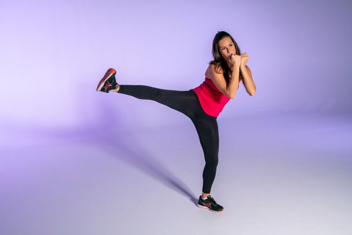 Stephanie Mansour throws a side kick while demonstrating kickboxing exercises.