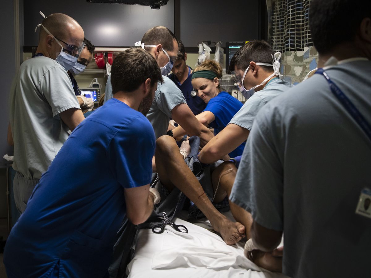 Medical workers perform their duties from specific positions around the bed as they treat a man with a stab wound at Mount Sinai Hospital.