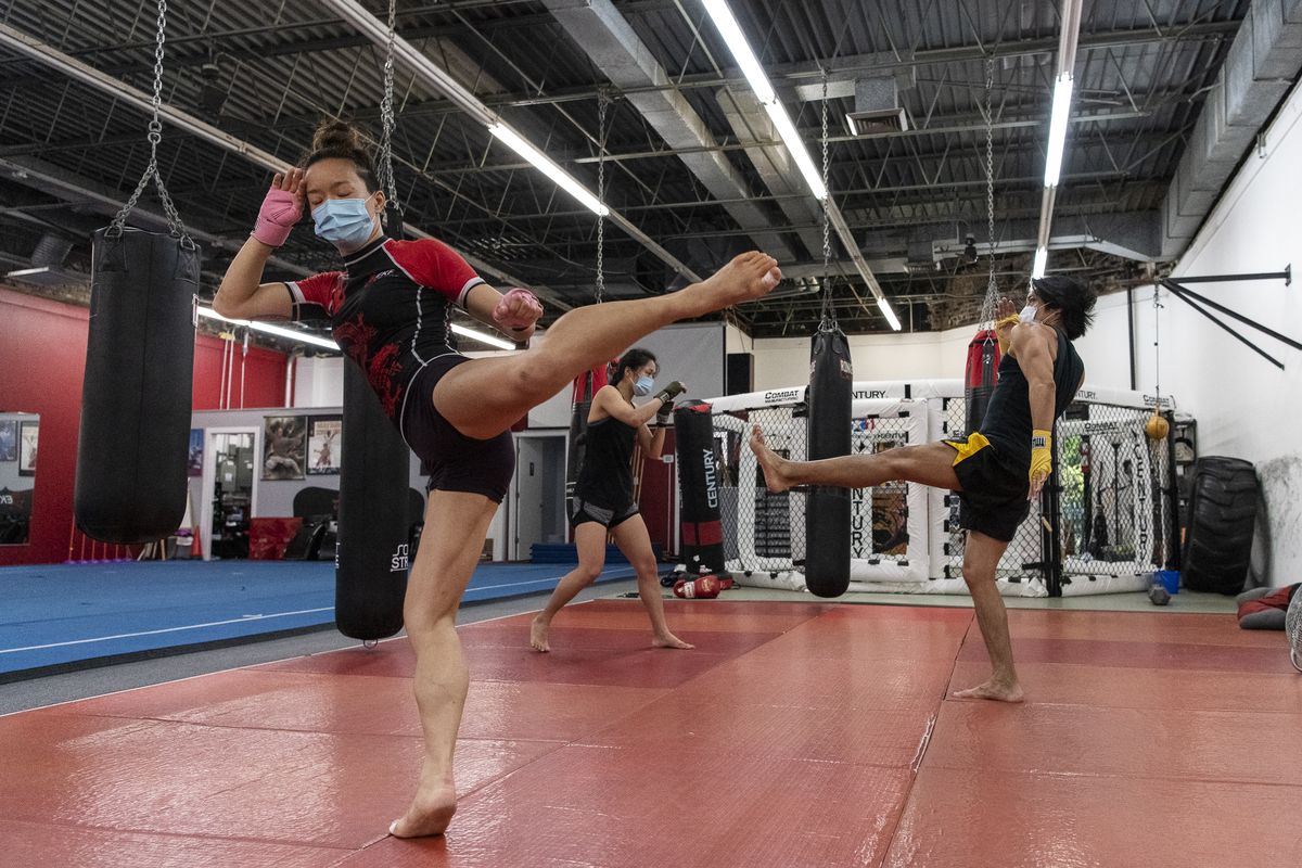 Lan Phan, left, and Jun Phan, center, follow along with Anthony Marquez owner and head coach at EFK Martial Arts, 5951 N. Clark St., during a boxing class on the first day of Illinois’ Phase 4 reopening, Friday, June 26, 2020.