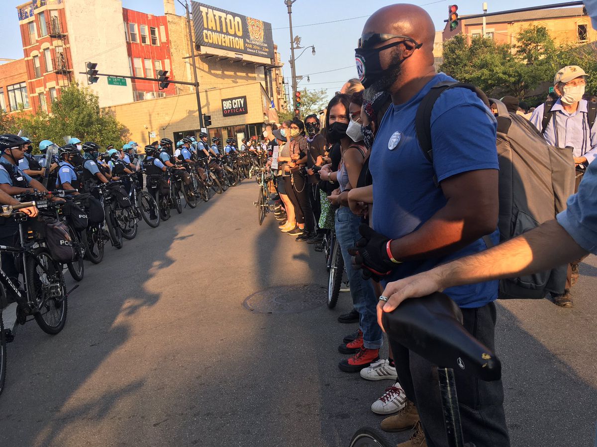 Demonstrators and police line up at 18th and Loomis streets on Saturday during a march in support of the family of Miguel Vega, who was fatally shot by police earlier this week in the neighborhood. 